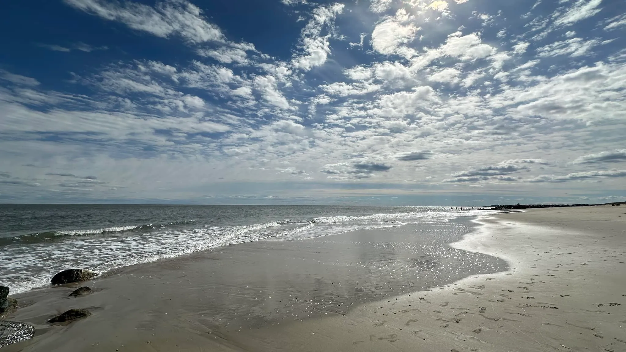 A pristine sandy beach with gentle waves under a sun-filled sky