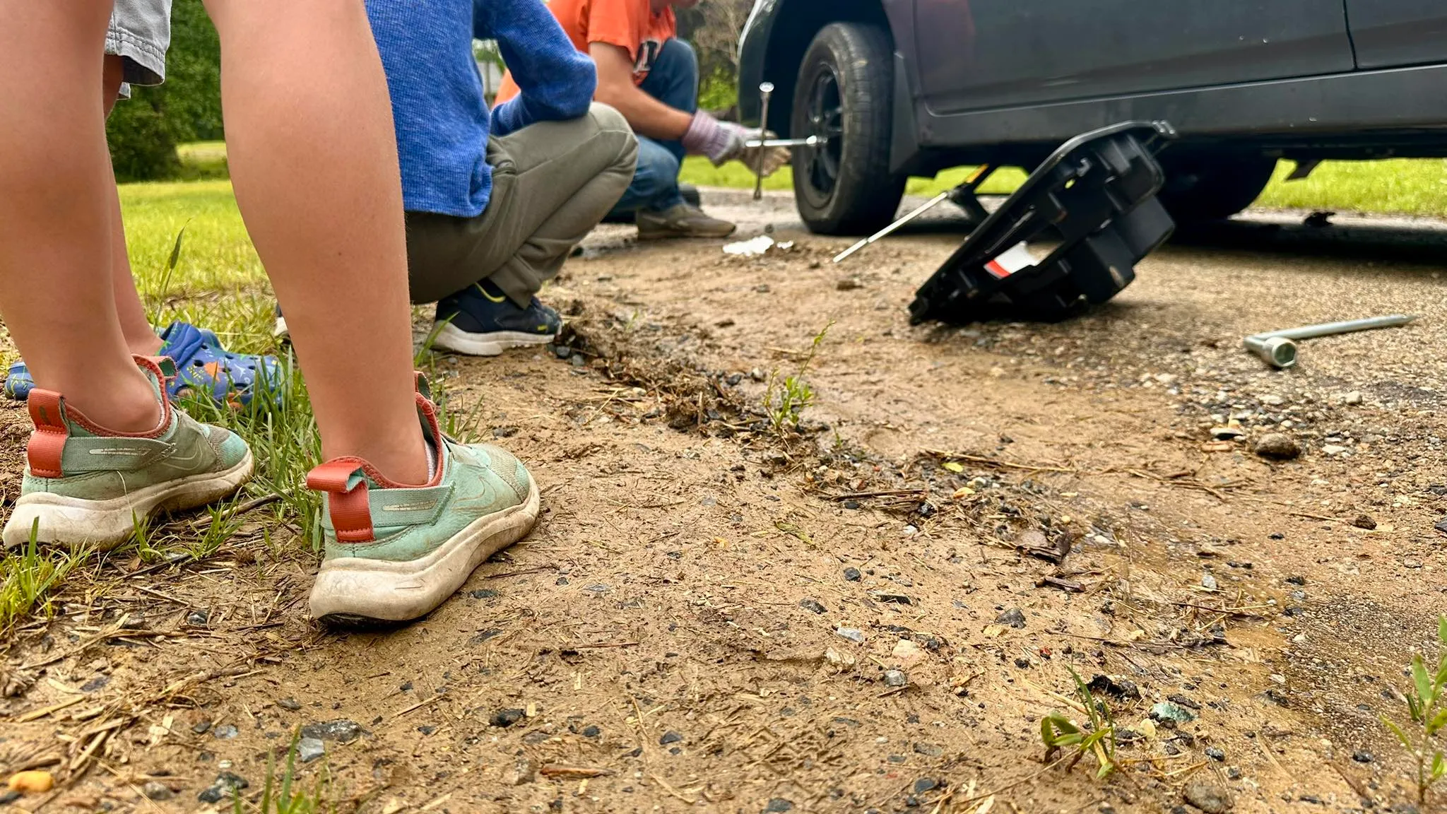 A flat tire being changed on the side of a road