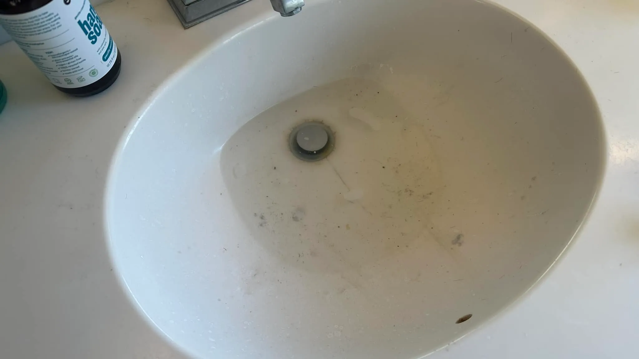 A bathroom sink with water pooling as it slowly drains